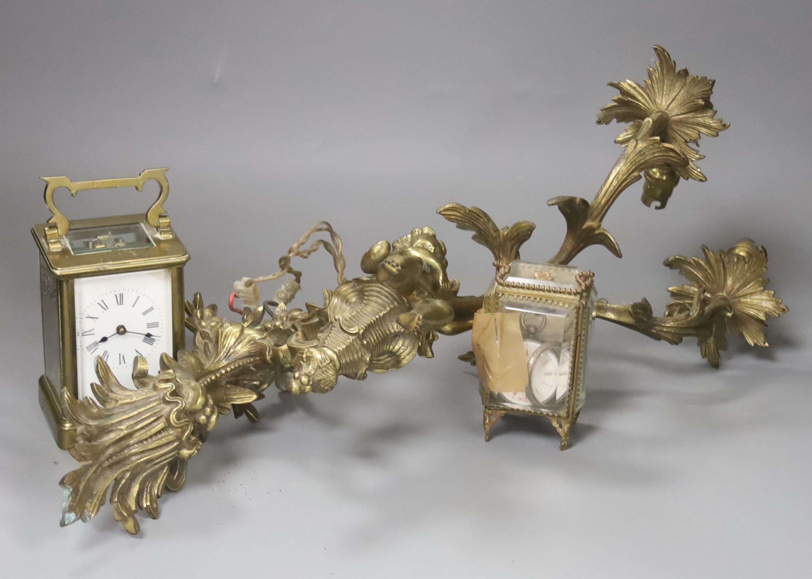 A brass carriage timepiece, a brass casket containing silver watch and a brass rococo-style twin-sconce wall light